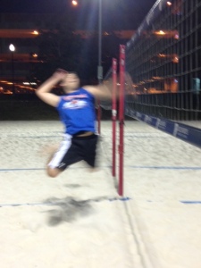 Soaring in the air to spike the ball. 